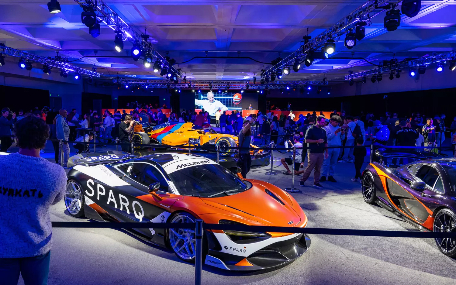 Supercars under stage lighting at an indoor automotive showcase