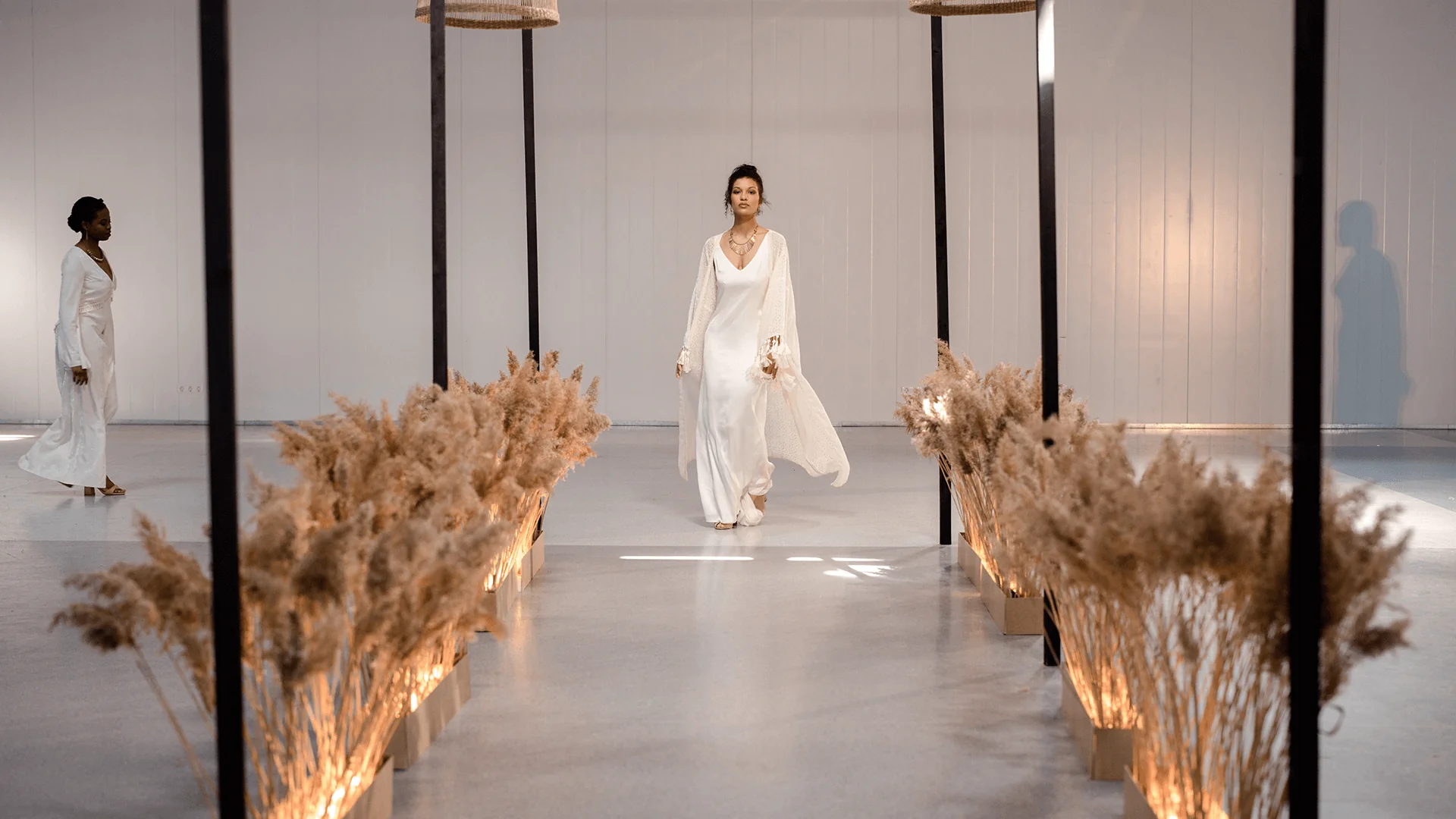Model walking a minimalist runway with warm lighting